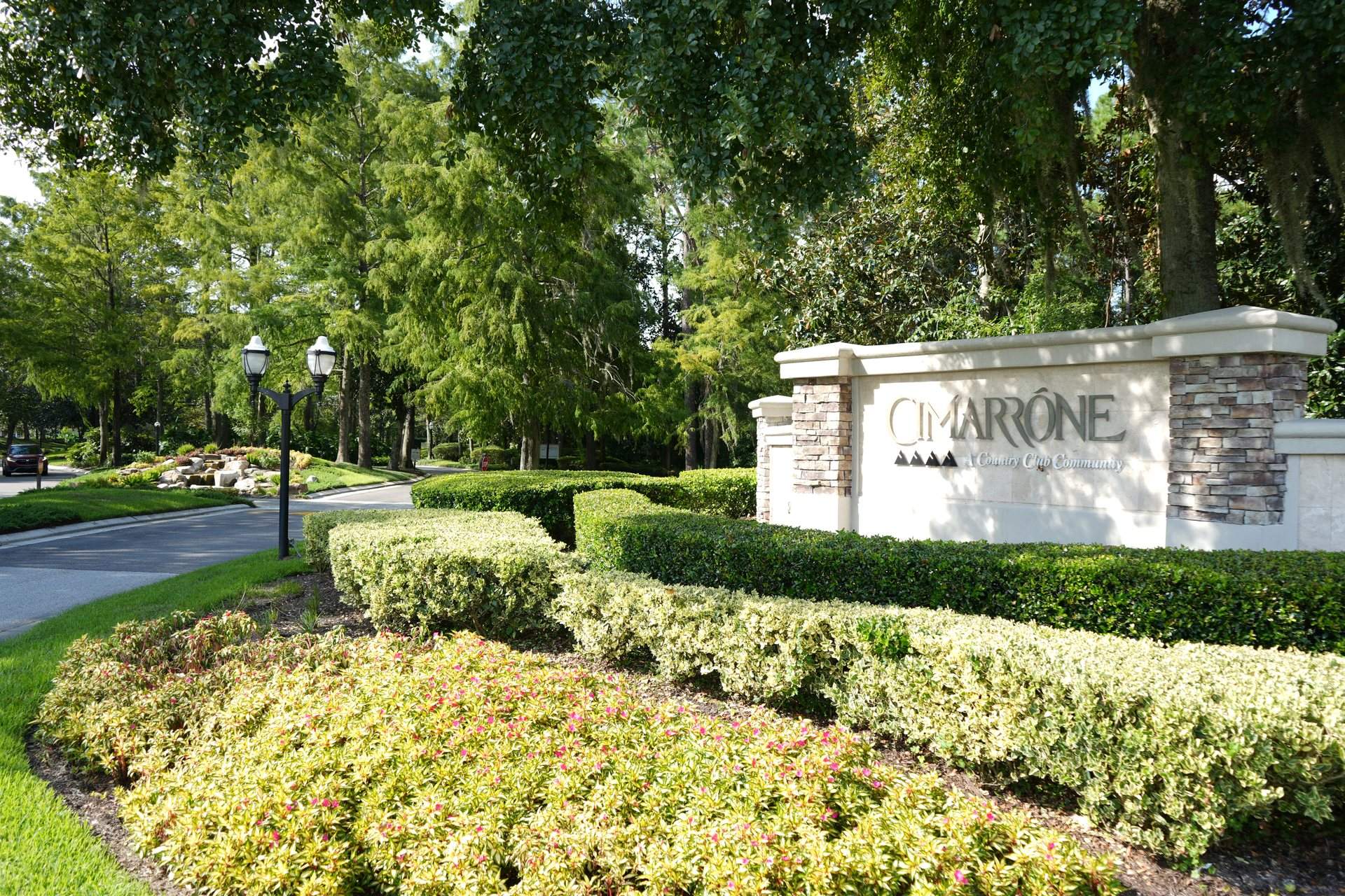 Cimarrone country club community entrance monument with lamp posts and a landscaped drive