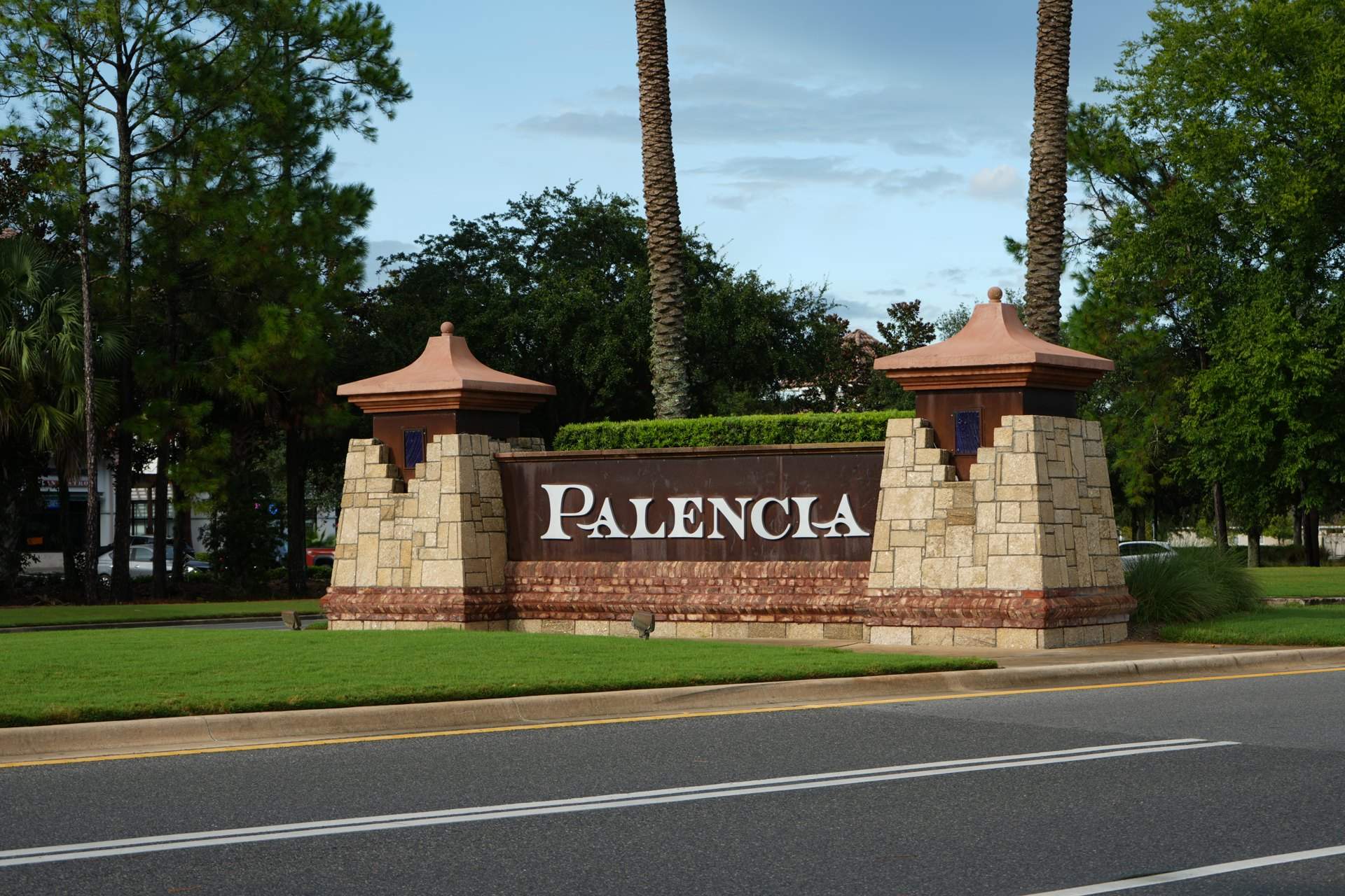 Palencia community entrance monument with stone pillars and palms