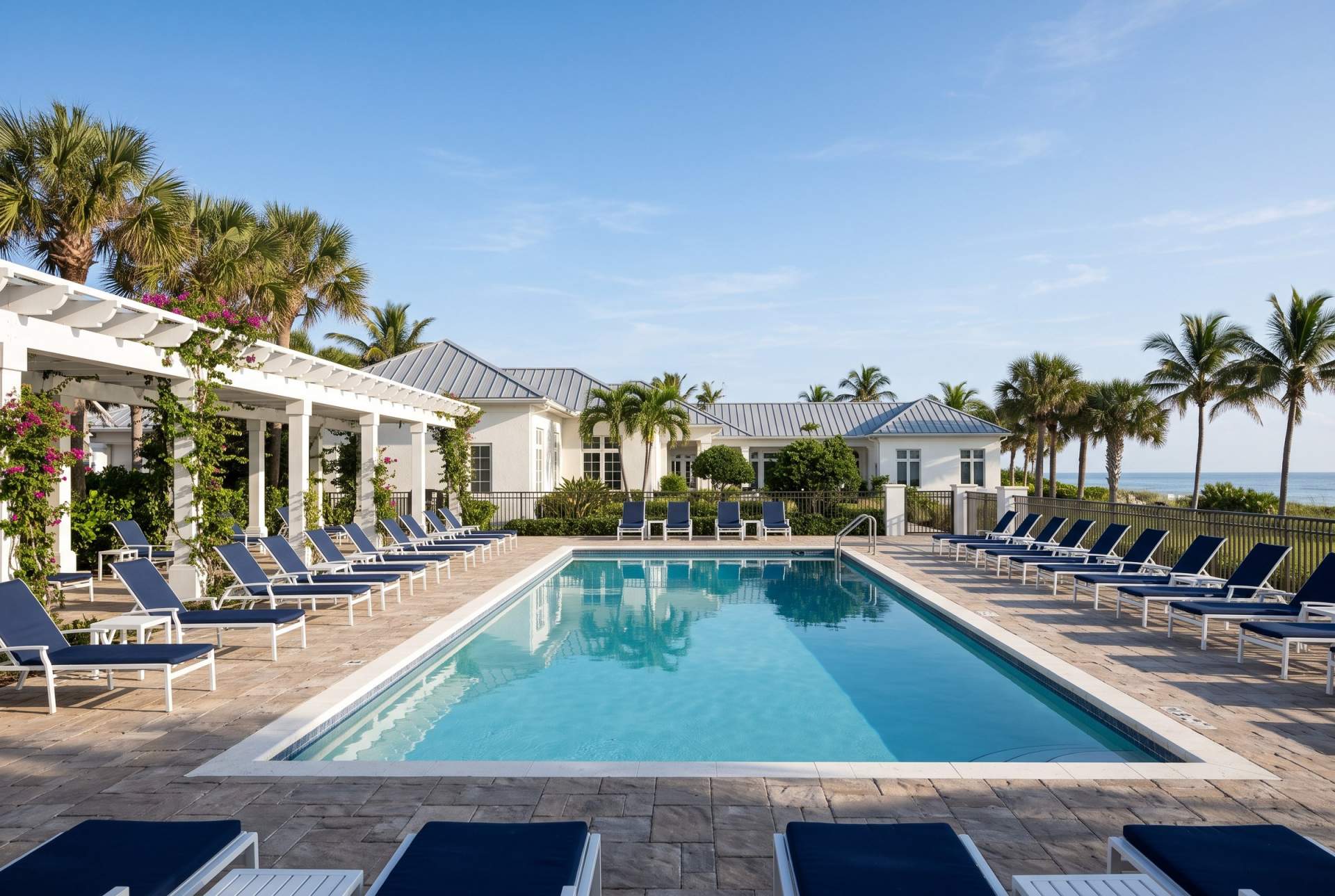 An upscale club pool terrace with white loungers and palms
